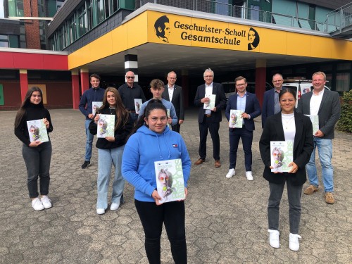 Spielt auch in diesem Jahr eine große Rolle an der Geschwister-Scholl-Gesamtschule. Der IHK-Ausbildungsatlas überreicht durch Hauptgeschäftsführer Axel Martens (3.v.l.) und Präsident Volker Steinbach (4.v.l.). Schulleiter Christoph Trappe (1.v.r.) und Schüler:innen freuen sich.